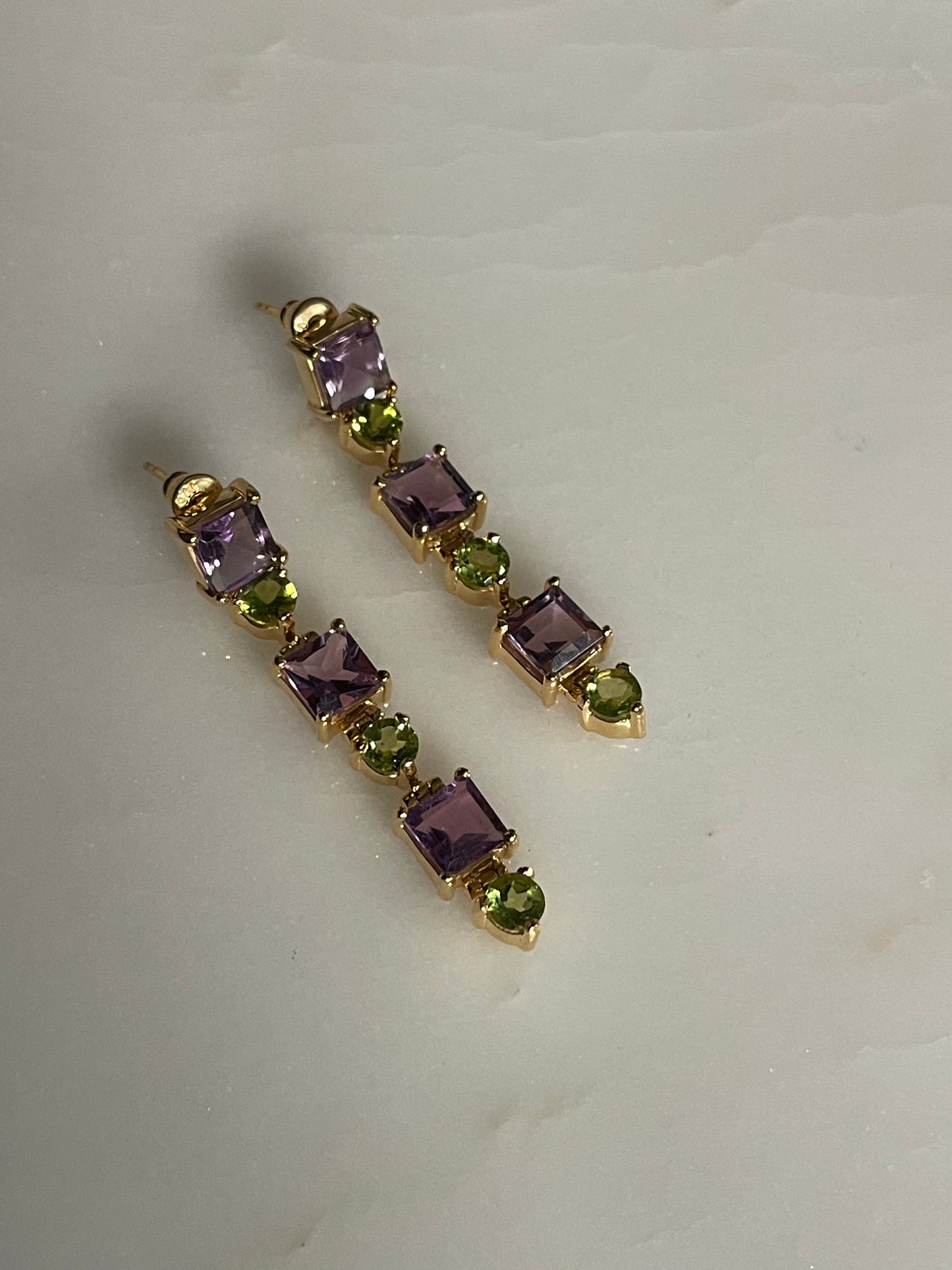 Pair of gold earrings with purple and green gemstones