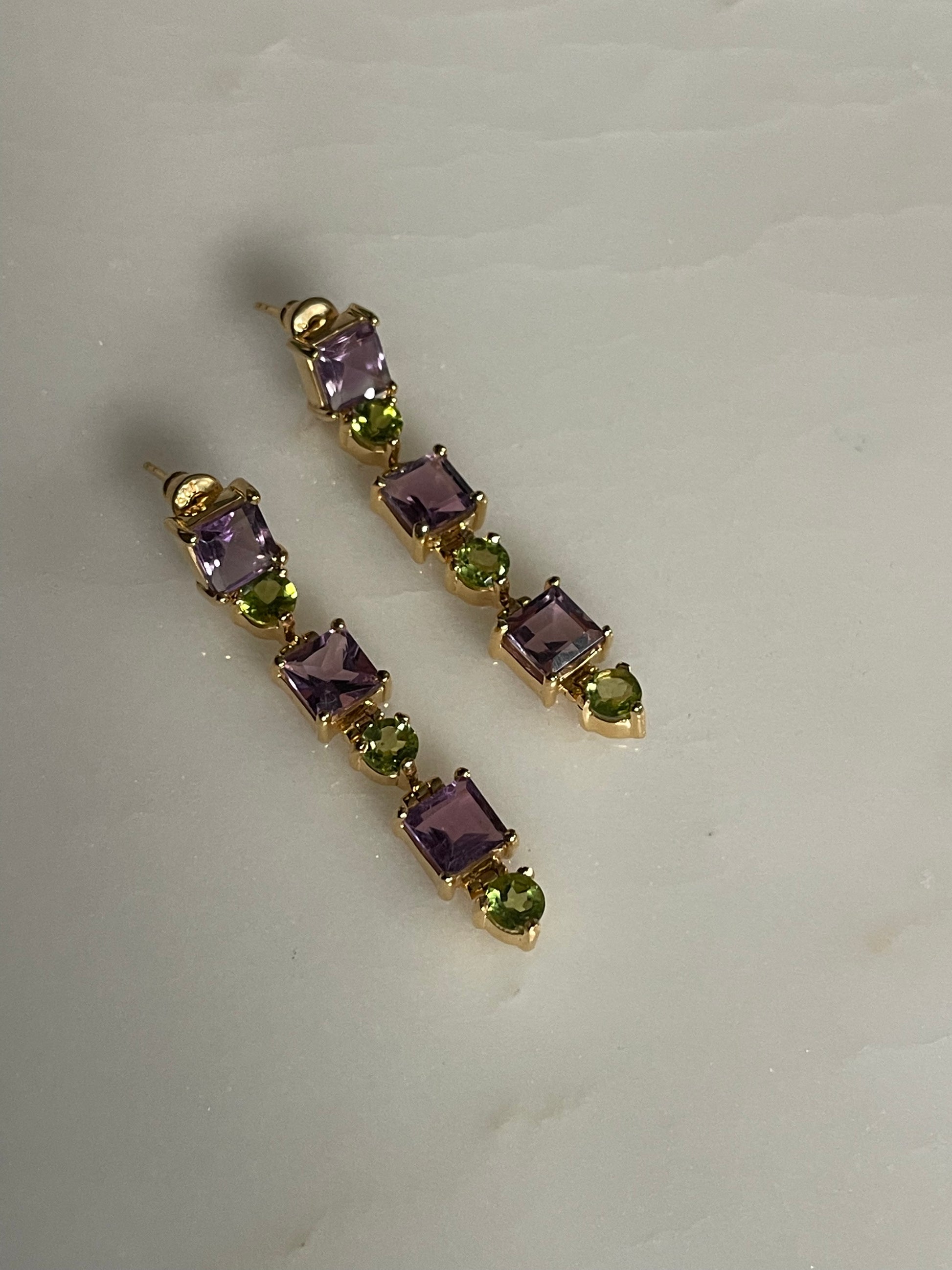 Pair of gold earrings with purple and green gemstones 
