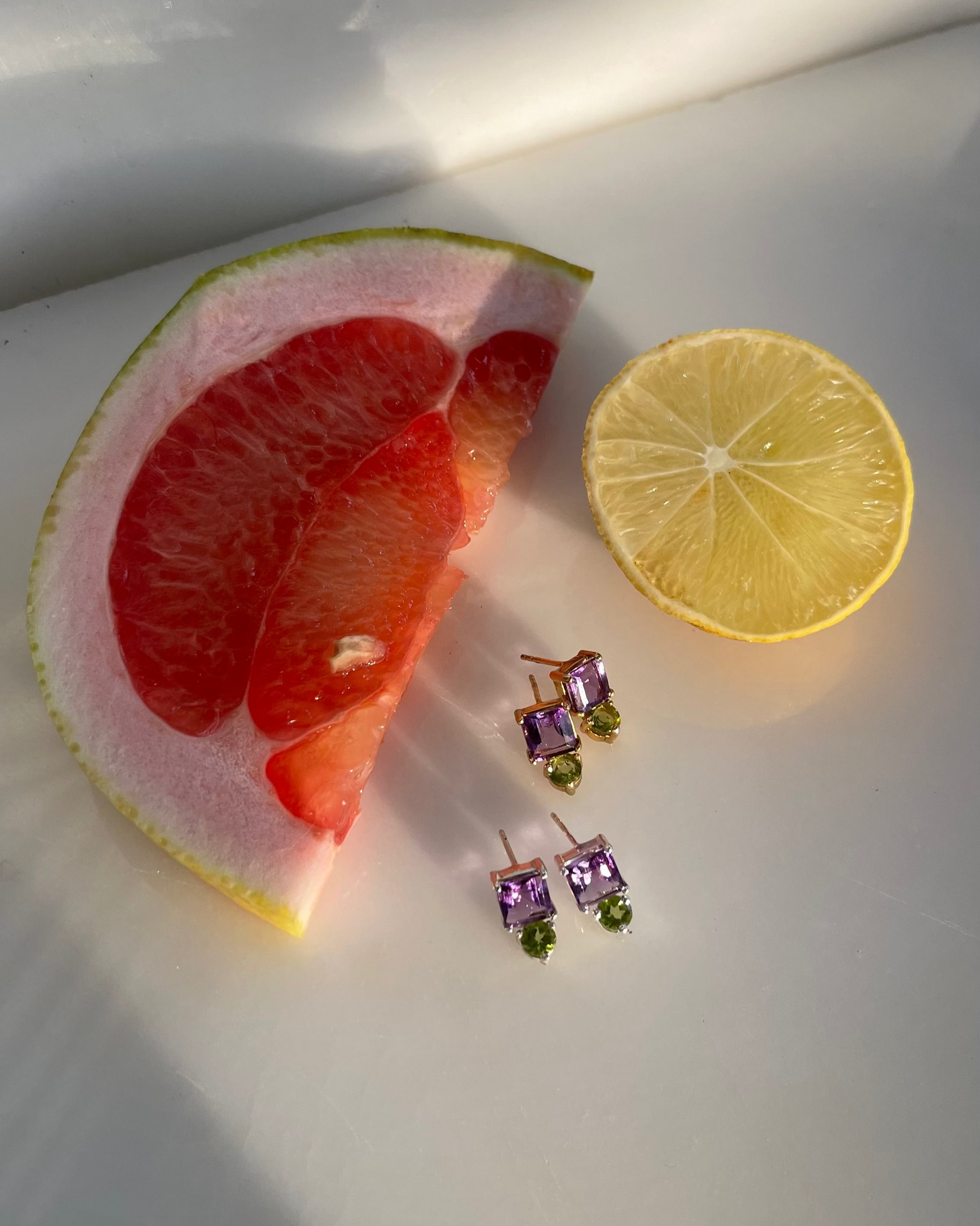 a pair of earrings with amethyst and peridot